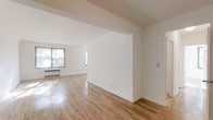 Located at 112 Hoyt St in Stamford, Connecticut, this two-bedroom, one-bathroom residence offers a well-designed single-floor layout with a clean, minimalist aesthetic. The living area is bright and open, benefiting from multiple windows that allow natural light to pour in and illuminate the warm-toned hardwood floors throughout. The crisp white walls create a neutral backdrop that enhances the sense of openness and makes the space feel airy and welcoming. The open-plan design between the main living and adjoining areas provides a seamless flow, making the layout feel expansive and functional. Baseboard heating ensures year-round comfort, and the understated architectural details — including clean wall lines and subtle structural divisions — give the unit a modern yet timeless character. The two bedrooms offer private retreats, while the shared bathroom serves the unit's residents with practicality. The overall ambiance of the space is light, fresh, and move-in ready, making it well-suited for those seeking a comfortable and low-maintenance residence in the Stamford area.