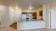 This single-floor 2-bedroom, 2-bathroom residence is designed with a practical and comfortable layout that makes excellent use of its space. The open-concept kitchen and living area serves as the heart of the home, featuring a generous peninsula countertop with grey laminate surfaces that doubles as a breakfast bar. The kitchen is outfitted with rich, warm-toned wood cabinetry, ample storage, and a full suite of white appliances including a refrigerator, range, and built-in microwave. The transition from wood-look flooring in the kitchen to plush carpeting in the living area creates a natural distinction between spaces. The bedrooms are well-proportioned, carpeted for comfort, and include sliding closet doors with vertical blinds that allow for natural light control. The two bathrooms offer distinct configurations: one features a full tub-shower combination with chrome fixtures and wood-look flooring, while the second bathroom includes a separate shower, a wood-toned vanity with an undermount sink, and matching flooring. Warm, neutral wall tones flow throughout the entire residence, creating a cohesive and inviting ambiance. The overall design prioritizes functionality and ease of living across every room.