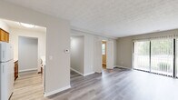 Located at 6870 E Livingstone Ave in Reynoldsburg, Ohio, this single-floor, 3-bedroom, 2-bathroom home offers a clean and functional layout with consistent light-toned luxury vinyl plank flooring throughout. The open living area provides a welcoming common space, with access to a patio through vertical-blind sliding doors that allow natural light to fill the room. A central hallway connects the bedrooms and bathrooms, with warm-toned cabinetry visible from the corridor offering a preview of the kitchen beyond. The galley-style kitchen is efficiently designed, featuring rich honey-toned wood cabinetry, white countertops, and white appliances including a refrigerator and coil-top range, with ample upper and lower cabinet storage. The three bedrooms are well-proportioned, each finished with the same light vinyl flooring, neutral walls, and windows fitted with blinds that overlook greenery outside. Bedrooms include bifold closet doors providing organized storage. The primary bedroom is notably spacious. The two bathrooms are clean and simply appointed; one features a full tub-shower combo with white subway tile surround, a vanity, and a mirror. Textured ceilings are present throughout, adding subtle character to the overall neutral, move-in-ready aesthetic of the home.