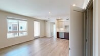 This 620-square-foot, one-bedroom, one-bathroom apartment at North Grove in Riverside, CA, delivers a modern and efficient living experience across a single floor. The open-concept kitchen and living area features light wood-style flooring, recessed lighting, and a sleek, contemporary kitchen outfitted with two-tone cabinetry, a subway tile backsplash, quartz countertops, and a full suite of stainless steel appliances including a French door refrigerator, electric range, over-the-range microwave, and dishwasher. The living area extends toward a glass door leading to a balcony with open views of the well-maintained North Grove community and surrounding mountain backdrop. The 120-square-foot bedroom is carpeted and filled with natural light from large windows that frame views of the community. It connects to a dedicated walk-in closet with wire shelving for organized storage. A hallway leads to the full bathroom, which features light wood-look flooring, a single-sink vanity with wood-toned cabinetry, a large mirror, and a full tub/shower combination. Clean, neutral tones and contemporary finishes throughout create a cohesive, move-in-ready atmosphere.