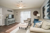 Located at 1045 Flynt Dr in Flowood, Mississippi, this single-floor, three-bedroom, two-bathroom home offers a well-organized layout designed for comfortable everyday living. The living room serves as the heart of the home, featuring durable wood-look flooring, a ceiling fan with light fixture, a textured ceiling, and a sliding glass door that fills the space with natural light and provides access to the outdoors. The kitchen is designed for functionality, offering light wood cabinetry, laminate countertops, and black appliances including a range, dishwasher, and refrigerator, all set atop matching wood-look flooring. A closet adjacent to the kitchen adds convenient storage. The primary bedroom is a comfortable retreat with plush carpeting, a ceiling fan, and a window for natural light, complemented by an en-suite bathroom featuring wood-look flooring, a vanity with sink, and a shower-tub combination. The two additional bedrooms are similarly appointed with soft carpet and windows, offering flexibility for guests, a home office, or family use. A second full bathroom serves these rooms. Neutral gray tones throughout the home create a clean, cohesive aesthetic that is both modern and welcoming.
