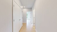 Located at 2540–2590 Lonsdale Avenue in North Vancouver, this well-appointed three-bedroom, two-bathroom residence offers a clean, contemporary design across a single level. Light hardwood flooring runs throughout the living areas and bedrooms, complementing the neutral grey-white palette that gives the space a bright, airy feel.

The open-concept living and dining area connects seamlessly to the kitchen, which features modern cabinetry and stainless steel appliances. Large floor-to-ceiling windows flood the space with natural light and frame lush, tree-lined views — a standout feature of the primary bedroom, which benefits from its generous proportions and direct outdoor vistas through expansive glazing with balcony access.

The two additional bedrooms are well-sized and versatile, each finished with the same warm hardwood flooring and clean white walls. A dedicated closet provides convenient storage. Both bathrooms are finished to a high standard, featuring marble-effect floor and wall tiling, soaker tubs with overhead showers, and sleek floating vanities with undermount sinks and chrome fixtures.

Two hallways connect the rooms efficiently, contributing to a practical and flowing layout. The overall ambiance is modern and understated, with quality finishes throughout that reflect a thoughtfully designed residential space in one of North Vancouver's well-connected neighbourhoods.