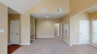 Located at 15035 Westpark Dr in Houston, TX, this single-floor unit offers a thoughtfully designed layout with a range of notable architectural features. The living room immediately impresses with its dramatic vaulted ceilings that rise to a striking height, flanked by clerestory windows that flood the space with abundant natural light. A tiled fireplace serves as a focal point, while multiple large windows offer lush outdoor views. Plush carpeting and warm, neutral-toned walls create an inviting ambiance throughout.

The galley-style kitchen is efficiently arranged with rich wood cabinetry, light granite countertops, hardwood flooring, and black appliances, providing a functional and attractive workspace. Built-in shelving in the living area adds both character and practicality.

The bedrooms continue the warm aesthetic with soft carpeting and generous ceiling heights. One bedroom features a sliding glass door that opens to a private balcony overlooking greenery, accompanied by a ceiling fan for added comfort. The bathroom is well-appointed with a granite vanity, wood cabinetry, a tiled tub-shower combination, and hardwood flooring, rounding out a cohesive and comfortable living space.