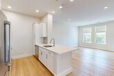 Located at 95 Fawcett Street in Cambridge, MA, this thoughtfully designed one-bedroom, one-bathroom unit offers a clean, modern aesthetic across a single floor. The open-concept kitchen and living area serves as the heart of the home, anchored by a striking white kitchen island with a quartz countertop and integrated sink. White shaker cabinetry, a subway tile backsplash, and a full suite of stainless steel appliances—including a French door refrigerator, microwave, and gas range—complete the kitchen. Light hardwood flooring flows seamlessly throughout the entire unit, enhancing the bright, airy atmosphere created by recessed lighting and well-placed windows that invite natural light. The living area offers an open, flexible layout with a calm, neutral palette. The generously sized primary bedroom features a window with an outdoor view, recessed lighting, and ample wall space. The full bathroom is finished with a white shaker vanity, stone-topped sink, subway tile tub surround, and wood-look tile flooring, maintaining the unit's cohesive modern style. Additional storage is provided by a louvered closet near the entryway. This unit presents a fresh, move-in-ready living experience in a desirable Cambridge location.