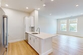 Located at 95 Fawcett Street in Cambridge, MA, this thoughtfully designed one-bedroom, one-bathroom unit offers a clean, modern aesthetic across a single floor. The open-concept kitchen and living area serves as the heart of the home, anchored by a striking white kitchen island with a quartz countertop and integrated sink. White shaker cabinetry, a subway tile backsplash, and a full suite of stainless steel appliances—including a French door refrigerator, microwave, and gas range—complete the kitchen. Light hardwood flooring flows seamlessly throughout the entire unit, enhancing the bright, airy atmosphere created by recessed lighting and well-placed windows that invite natural light. The living area offers an open, flexible layout with a calm, neutral palette. The generously sized primary bedroom features a window with an outdoor view, recessed lighting, and ample wall space. The full bathroom is finished with a white shaker vanity, stone-topped sink, subway tile tub surround, and wood-look tile flooring, maintaining the unit's cohesive modern style. Additional storage is provided by a louvered closet near the entryway. This unit presents a fresh, move-in-ready living experience in a desirable Cambridge location.
