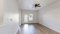 Located in Carmel, Indiana, this well-designed one-bedroom, one-bathroom unit offers a practical and comfortable single-floor layout. Warm hardwood-style flooring flows consistently throughout every room, creating a cohesive and inviting ambiance. The combined kitchen and living area forms the heart of the space. The galley-style kitchen is well-appointed with white shaker cabinetry, granite countertops, a stainless steel refrigerator, range, and dishwasher, along with a deep single-basin sink — providing ample functionality in a compact footprint. The living room benefits from natural light through a glass exterior door and adjacent window, complemented by a ceiling fan with integrated lighting. The bedroom is a comfortable, well-proportioned retreat featuring two windows with blinds that allow generous natural light, a ceiling fan, and a double-door closet for storage. The bathroom is thoughtfully outfitted with a granite-topped vanity with an undermount sink, a walk-in shower with grab bars for added accessibility, and matching cabinetry hardware. A hallway connects the main living areas to the bedroom and bathroom, ensuring a logical and efficient flow throughout the unit.