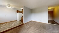 Located at 4008 S Louise Ave in Sioux Falls, South Dakota, this single-floor, 2-bedroom, 1-bathroom unit offers a practical and functional layout. The interior features neutral gray walls and carpet throughout the main living and bedroom areas, complemented by wood-toned trim and doors that add warmth to the space.

The combined dining room and kitchen area is distinguished by hard-surface flooring, dark wood cabinetry, and a white refrigerator, with a pass-through counter that connects it to the carpeted living room. The living room is open and receives natural light from a sliding window with an outdoor view.

Both bedrooms are carpeted and well-sized, with the primary bedroom featuring a large sliding wood-panel closet and a window overlooking greenery outside. The second bedroom also includes a window with natural light and baseboard heating. Altogether, the unit includes four closets, providing generous storage options.

The bathroom is clean and straightforward, featuring a full tub and shower combination with white surround panels. Two hallways connect the rooms efficiently throughout the single-level floor plan. Baseboard heating is present across multiple rooms, ensuring consistent climate control. The textured ceilings add a classic residential character to the overall interior.