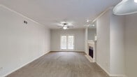 This single-floor, two-bedroom, two-bathroom residence in Memphis, Tennessee offers a thoughtfully designed layout with comfortable finishes throughout. The living area is a generous, open space featuring plush carpeting, crown molding, a ceiling fan, and a tiled fireplace flanked by a mirrored accent wall. French doors flood the room with natural light and provide direct access to the outdoors. A separate dining area features a pendant light fixture and a large window framing lush greenery views, creating a bright and inviting atmosphere. The galley-style kitchen is well-appointed with granite countertops, white cabinetry, wood-look flooring, and white appliances including a range, microwave, refrigerator, and dishwasher. A pass-through opening connects the kitchen to the dining area, enhancing the flow between spaces. Both bedrooms are carpeted and feature ceiling fans and ample natural light from well-positioned windows. Each bedroom includes access to a walk-in or standard closet, providing generous storage. The bathrooms are finished with granite vanity countertops and wood-look flooring, maintaining a consistent aesthetic throughout the home. Crown molding and neutral tones tie the entire residence together, creating a clean and cohesive living environment.
