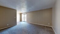 Located at 3101 SW Twilight Ct in Topeka, Kansas, this single-story unit offers a straightforward, functional layout with neutral warm-toned walls and textured ceilings throughout. The living area is generously sized, finished with plush gray carpeting and a ceiling fan with light fixture. A sliding glass door at one end of the room provides access to an outdoor area and brings in natural light, creating a bright, open atmosphere.

The galley-style kitchen is well-equipped, featuring warm wood-toned cabinetry with ample upper and lower storage, light granite-style countertops, a stainless steel refrigerator and over-the-range microwave, and a black electric range. Wood-look hard-surface flooring adds durability and easy maintenance to this space.

The bedroom offers comfortable carpeted flooring, natural light from a window with blinds, and two closets—one of which is a reach-in closet with a hanging rod—providing generous storage. Additional living or flex spaces feature the same gray carpeting and neutral tones, offering versatile use.

The bathroom is cleanly appointed with a white vanity, tub/shower combo with tiled surround, and wood-look flooring, maintaining a consistent, cohesive aesthetic throughout the unit.