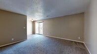 Located at 3101 SW Twilight Ct in Topeka, Kansas, this single-story unit offers a straightforward, functional layout with neutral warm-toned walls and textured ceilings throughout. The living area is generously sized, finished with plush gray carpeting and a ceiling fan with light fixture. A sliding glass door at one end of the room provides access to an outdoor area and brings in natural light, creating a bright, open atmosphere.

The galley-style kitchen is well-equipped, featuring warm wood-toned cabinetry with ample upper and lower storage, light granite-style countertops, a stainless steel refrigerator and over-the-range microwave, and a black electric range. Wood-look hard-surface flooring adds durability and easy maintenance to this space.

The bedroom offers comfortable carpeted flooring, natural light from a window with blinds, and two closets—one of which is a reach-in closet with a hanging rod—providing generous storage. Additional living or flex spaces feature the same gray carpeting and neutral tones, offering versatile use.

The bathroom is cleanly appointed with a white vanity, tub/shower combo with tiled surround, and wood-look flooring, maintaining a consistent, cohesive aesthetic throughout the unit.