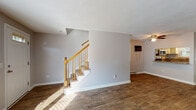 Located at 17 Briarwood Dr in Attleboro, Massachusetts, this two-floor home offers a well-organized layout with distinct living spaces across each level. The main floor features wide-plank, hardwood-style flooring throughout the living and dining areas, complemented by neutral gray walls that create a clean, cohesive aesthetic. Natural light filters in through multiple windows fitted with blinds, brightening the open living spaces. A staircase with warm wood railings connects the two floors, and a convenient closet is situated near the entry area.

The kitchen is thoughtfully appointed with white cabinetry, granite-style countertops, a subway tile backsplash, and stainless steel appliances including a range, microwave, and dishwasher. A window above the sink provides natural light. A bathroom on this level features wood-look tile flooring, a white vanity, and clean, bright finishes with a wainscoted lower wall.

Upstairs, the bedrooms are carpeted and well-sized, each with natural light from windows and baseboard heating. The primary bedroom is notably spacious, offering two separate closets with built-in shelving. An additional full bathroom upstairs includes wood-look tile flooring and practical grab bar hardware. Throughout the home, baseboard heating is consistently present, ensuring comfort across all rooms.