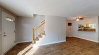 Located at 17 Briarwood Dr in Attleboro, Massachusetts, this two-floor home offers a well-organized layout with distinct living spaces across each level. The main floor features wide-plank, hardwood-style flooring throughout the living and dining areas, complemented by neutral gray walls that create a clean, cohesive aesthetic. Natural light filters in through multiple windows fitted with blinds, brightening the open living spaces. A staircase with warm wood railings connects the two floors, and a convenient closet is situated near the entry area.

The kitchen is thoughtfully appointed with white cabinetry, granite-style countertops, a subway tile backsplash, and stainless steel appliances including a range, microwave, and dishwasher. A window above the sink provides natural light. A bathroom on this level features wood-look tile flooring, a white vanity, and clean, bright finishes with a wainscoted lower wall.

Upstairs, the bedrooms are carpeted and well-sized, each with natural light from windows and baseboard heating. The primary bedroom is notably spacious, offering two separate closets with built-in shelving. An additional full bathroom upstairs includes wood-look tile flooring and practical grab bar hardware. Throughout the home, baseboard heating is consistently present, ensuring comfort across all rooms.