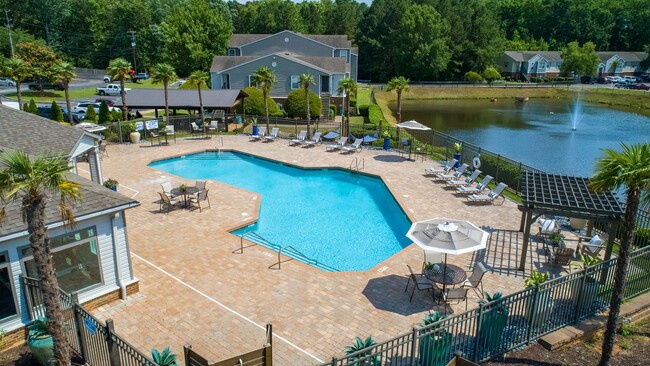 An aerial view showcases our gleaming pool, lush greenery, and serene lakeside charm. - River Bluff of Lexington