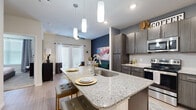 Located at 14625 Potranco Rd in San Antonio, TX, this well-designed one-bedroom, one-bathroom unit offers a smart, efficient layout across a single floor. The open-concept living and kitchen area serves as the heart of the home, featuring a large granite-topped island with an undermount sink and stylish pendant lighting overhead — ideal for both meal prep and casual dining. Dark wood cabinetry with modern hardware complements the stainless steel appliances, including a refrigerator, electric range, and built-in microwave. A bold navy accent wall adds a contemporary touch to the living area, which is filled with natural light from large windows and a sliding glass door leading to the private patio. The bedroom is a comfortable retreat, carpeted and bright, with multiple windows, a ceiling fan, and a warm accent wall. A spacious walk-in closet with wire shelving provides ample storage. The bathroom includes a granite-topped vanity with dark cabinetry, wood-look flooring, and a full tub/shower combination. A dedicated in-unit laundry area with a full-size washer and dryer adds everyday convenience. Wood-look flooring flows throughout the main living areas, tying the space together with a clean, modern aesthetic.