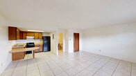 Located at 910 S Volusia Ave in Orange City, Florida, this single-floor unit offers a practical and efficient layout across a cozy footprint. Light-colored ceramic tile flooring runs consistently throughout the entire space, lending a clean, cohesive look to every room.

The open living area features bright white walls, a wall-mounted HVAC unit, and a front entry door with decorative glass panes that allow natural light to filter in. A window overlooking greenery adds to the airy feel of the main room.

The kitchen is well-appointed with warm oak cabinetry — both upper and lower — providing generous storage space. A skylight overhead brightens the work area, which includes a double-basin stainless steel sink, a gas range, a black refrigerator, and light laminate countertops. A built-in breakfast bar extends from the counter, offering a convenient casual dining option that opens directly to the living area.

The bathroom includes a full tub and shower combination featuring distinctive marbled surround walls, a toilet, and a vanity with storage. A closet provides additional storage within the unit.

Overall, the space presents a straightforward, functional design with a neutral palette, making it easy to personalize and well-suited for efficient everyday living.