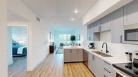 Located at 850 N Azusa Ave in Azusa, CA, this well-appointed 2-bedroom, 1-bathroom unit offers a thoughtfully designed open-concept layout across a single floor. Light wood flooring runs throughout, creating a warm and cohesive aesthetic that ties each space together seamlessly.

The kitchen is a standout feature, showcasing gray shaker cabinets with matte black hardware, white quartz countertops, a subway tile backsplash, and a full suite of stainless steel appliances. A peninsula with seating provides additional counter space and a natural transition into the living area, which benefits from large windows that fill the room with natural light and offer open views of the surrounding neighborhood.

The spacious primary bedroom includes sliding glass door access to a private balcony, offering scenic outdoor views and abundant natural light. A hallway reveals a stacked in-unit washer and dryer, adding practical convenience. The bathroom is clean and functional, featuring a shower/tub combination, wood-look flooring, and crisp white finishes throughout. Recessed lighting, white walls, and consistent flooring across the unit contribute to a bright, modern ambiance ideal for comfortable everyday living.
