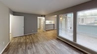 This thoughtfully designed 2-bedroom, 2-bathroom residence spans a single floor, offering a functional and comfortable layout. The open living and dining area features wood-style plank flooring and large windows fitted with blinds, allowing generous natural light to fill the space. An accent wall with white brick-style texture adds a distinctive architectural touch to the living area. The kitchen is accessible via a pass-through bar counter, providing a convenient connection between the cooking and living spaces.

Both bedrooms are carpeted for warmth and comfort, each equipped with ceiling fans and windows that invite natural light. One bedroom features a built-in storage unit with louvered cabinet doors, open shelving, and hanging space, offering practical organization solutions.

The two bathrooms share a consistent design aesthetic, each featuring white vanity cabinetry with brushed nickel hardware, solid white countertops, lighted mirrors, and textured walls. Wood-look flooring carries through the bathroom spaces, complementing the rest of the home.

A wide hallway area also includes extended white cabinetry with a countertop surface and mirrored panels above, adding both storage and visual depth. Throughout the residence, neutral gray tones create a cohesive, modern atmosphere that is both versatile and inviting.