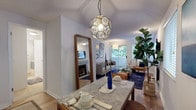 This thoughtfully designed single-floor residence offers a seamless blend of comfort and style across its key living spaces. The open-concept living and dining area serves as the heart of the home, featuring warm hardwood-style flooring, a striking geometric pendant light over the marble-topped dining table, and a curated gallery wall that adds character to the space. A large floor-length mirror enhances the sense of openness, while access to an outdoor area brings in natural light and lush greenery views.

The living room centers around a tiled fireplace flanked by windows, creating a welcoming focal point ideal for relaxing or entertaining. The kitchen is well-equipped with white shaker cabinetry, dark countertops, stainless steel appliances, and durable wood-look flooring for easy maintenance.

The primary bedroom offers plush carpeting, ample space, and a relaxed ambiance, while a second bedroom features a charming accent wall with book-print wallpaper and soft carpet underfoot. Both rooms are bright and comfortable. The two bathrooms are clean and functional, with tile flooring, a full bathtub with shower in one and a convenient half bath in the other. Overall, the space exudes a cozy yet polished atmosphere throughout.