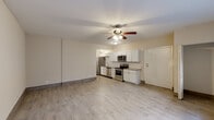 This two-floor space offers a clean, updated interior with a consistent design language throughout. The main living area is generously proportioned, featuring light wood-look tile flooring and neutral-toned walls that create a bright, airy atmosphere. Ceiling fans with integrated lighting fixtures are present in the living areas, contributing to both comfort and ambient illumination. Windows allow natural light to filter into the space, enhancing its open feel.

The kitchen is well-appointed with white shaker-style cabinetry, light countertops, and a classic subway tile backsplash. Stainless steel appliances include a range, over-the-range microwave, dishwasher, and refrigerator, providing a fully functional cooking environment. A double-basin stainless steel sink with a brushed nickel faucet completes the kitchen.

The bathroom features white subway tile in the shower/tub surround, maintaining the clean aesthetic found throughout the space. Additional rooms include a versatile lower-level area with wood-look tile flooring and exposed beam detailing, suitable for flexible use. Throughout the space, consistent flooring, neutral paint, and updated fixtures contribute to a cohesive, modern feel.