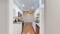 Located at 23939 Ocean Ave in Torrance, CA, this well-appointed single-floor residence offers two bedrooms and two bathrooms across a comfortable, efficiently designed layout. The galley-style kitchen is a standout feature, showcasing white shaker cabinetry, granite countertops, a decorative tile backsplash, stainless steel appliances, and recessed lighting. It opens toward the living area, which is enhanced by a ceiling fan and warm hardwood-style flooring that extends throughout the main living spaces. A central hallway with a textured ceiling connects the various rooms, providing a clean and organized flow. The spacious primary bedroom features soft carpeting, a window with vertical blinds that invites natural light, and mirrored sliding closet doors that add depth to the room. The primary bathroom includes a granite-topped vanity with white cabinetry, hardwood-style flooring, and convenient access to a dedicated laundry area. The second bedroom is similarly carpeted and naturally lit. Both bathrooms are well-appointed, with one featuring a tub-shower combination enclosed by a sliding glass door. The overall aesthetic is clean and neutral, with white walls, textured ceilings, and consistent finishes throughout.