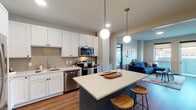 Located on Utica Ave S in St. Louis Park, MN, this thoughtfully designed single-floor residence offers a seamless blend of modern aesthetics and functional living. The open-concept kitchen serves as the heart of the home, showcasing crisp white shaker cabinetry, a herringbone tile backsplash, stainless steel appliances, and a striking teal center island with a white quartz countertop — illuminated by elegant globe pendant lights. Warm hardwood-style flooring flows throughout, connecting the kitchen to the living area, where large windows and a glass-panel door open onto a private balcony, filling the space with natural light and outdoor views.

The primary bedroom is a serene retreat featuring wide windows, soft neutral tones, and plush carpeting. Its en-suite bathroom offers a dual-sink vanity with white cabinetry, a large mirror with warm wood framing, and a walk-in closet with built-in shelving. A second well-appointed bedroom provides equal comfort, also benefiting from ample natural light. The second bathroom mirrors the home's refined design, featuring a marble-look countertop, white vanity, and a wood-framed mirror. Together, these spaces create a cohesive, contemporary living environment ideal for modern urban living.