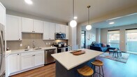 Located on Utica Ave S in St. Louis Park, MN, this thoughtfully designed single-floor residence offers a seamless blend of modern aesthetics and functional living. The open-concept kitchen serves as the heart of the home, showcasing crisp white shaker cabinetry, a herringbone tile backsplash, stainless steel appliances, and a striking teal center island with a white quartz countertop — illuminated by elegant globe pendant lights. Warm hardwood-style flooring flows throughout, connecting the kitchen to the living area, where large windows and a glass-panel door open onto a private balcony, filling the space with natural light and outdoor views.

The primary bedroom is a serene retreat featuring wide windows, soft neutral tones, and plush carpeting. Its en-suite bathroom offers a dual-sink vanity with white cabinetry, a large mirror with warm wood framing, and a walk-in closet with built-in shelving. A second well-appointed bedroom provides equal comfort, also benefiting from ample natural light. The second bathroom mirrors the home's refined design, featuring a marble-look countertop, white vanity, and a wood-framed mirror. Together, these spaces create a cohesive, contemporary living environment ideal for modern urban living.