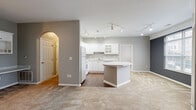 Located at 6049 Outpost Rd in Toledo, OH, this 2-bedroom, 1-bathroom residence offers a well-designed single-floor layout with a thoughtful blend of functionality and comfort. The open-concept living area is anchored by plush neutral carpeting and flows seamlessly into the kitchen, which features white cabinetry with glass-front accents, a peninsula island with a light stone countertop, white appliances, and track lighting overhead. A hardwood-style floor distinguishes the kitchen and entryway zones from the carpeted living spaces.

The entry hallway includes a built-in desk and shelving unit, providing a practical workspace nook, and leads through a charming arched doorway into the main living area. Large windows and a glass-paneled door in the living space invite generous natural light and outdoor views, complemented by a bold accent wall in deep gray.

The bedrooms are carpeted and serene, with the primary offering a comfortable, well-proportioned retreat. The bathroom is finished with tile flooring, a white vanity, and a full tub-shower combination. A dedicated closet provides added storage. Throughout, neutral gray walls, white trim, and consistent finishes create a clean, cohesive aesthetic.