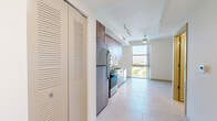 Located at 3180 Northwest 79th Street in Miami, FL, this efficiently designed single-floor unit offers a well-planned open-concept layout that combines the living, dining, and kitchen areas into one cohesive space. Large floor-to-ceiling windows flood the main living area with abundant natural light and frame panoramic views of the surrounding Miami cityscape, creating an airy and bright atmosphere despite the compact footprint.

The kitchen is thoughtfully appointed with light wood-grain cabinetry extending from floor to ceiling, granite countertops, a double-basin sink, and a full suite of stainless steel appliances including a refrigerator, range, built-in microwave, and dishwasher. The cabinetry features sleek gold-toned bar pulls, adding a refined touch to the contemporary design. Light-toned large-format ceramic tile flooring runs throughout the space, contributing to a clean and cohesive aesthetic.

The bathroom is finished in crisp white tones with light tile flooring, a combined shower and soaking tub, a toilet, and a wood-accented vanity with a granite countertop. Three closets provide generous storage solutions throughout the unit, including a dedicated walk-in closet with built-in shelving and rod organizers. A ceiling fan in the living area and track lighting in the kitchen further enhance the functionality of this well-designed Miami residence.
