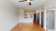 This thoughtfully designed one-bedroom, one-bathroom residence in Opelika, Alabama offers a clean, modern aesthetic throughout its efficiently arranged single floor. The open-concept layout seamlessly connects the living room, dining area, and kitchen, creating a bright and cohesive communal space. Warm hardwood-style flooring runs throughout the main living areas, complemented by crisp white walls and recessed lighting.

The kitchen is a standout feature, showcasing white upper cabinetry, natural wood-toned lower cabinets, a white quartz peninsula with pendant lighting overhead, a tiled backsplash, and a full suite of stainless steel appliances including a refrigerator, range, microwave, and dishwasher. The peninsula provides additional seating and prep space, and flows naturally into the living area, which is equipped with a ceiling fan and a window offering outdoor views.

The bedroom is carpeted for comfort, features a ceiling fan, and receives ample natural light through a large window with outdoor views. The bathroom is well-appointed with wood-tone vanity cabinetry, a white quartz countertop, a tiled tub-shower combination with matte black fixtures, and hardwood-style flooring. A dedicated closet and in-unit laundry add practical convenience to this well-finished residence.
