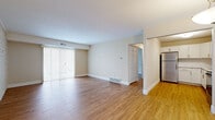Located at 1480 Carpenter Rd S in Brunswick, Ohio, this single-floor, three-bedroom, one-bathroom unit offers a well-organized layout across a comfortable footprint. The open living room is a standout space, featuring warm hardwood-style flooring, a striking accent wall clad in light-toned brick, and a large sliding glass door with vertical blinds that fills the room with natural light. Adjacent to the living area, the kitchen is efficiently designed in an L-shaped configuration with crisp white shaker cabinetry, stainless steel appliances including a refrigerator and dishwasher, a stainless undermount sink, and a pendant light overhead that adds a clean, modern touch. The three bedrooms are carpeted for comfort and each benefits from natural light through windows with blinds. The primary bedroom is a generous size and includes a walk-in closet outfitted with wire shelving for ample storage. The shared bathroom is neatly appointed with a white vanity, a framed mirror, and a tiled tub-shower combination with hardwood-style flooring extending throughout. Two hallways connect the rooms efficiently, completing a practical and well-maintained floor plan suited for everyday living.