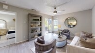 This single-story residence is designed with a neutral color palette and modern finishes that create a cohesive, contemporary atmosphere throughout. The living area serves as the heart of the home, featuring wood-look flooring, a ceiling fan, and a textured ceiling. Large sliding glass doors lead to a private balcony, filling the space with natural light and offering outdoor views. A built-in open shelving unit adds a functional architectural detail, while a round mirror reflects light across the room, enhancing the sense of openness.

The kitchen is efficiently laid out with white cabinetry, a stainless steel refrigerator, and a white countertop peninsula that doubles as a breakfast bar with seating. Under-cabinet lighting and gold-toned hardware add refined detail to the space.

The bedroom is carpeted for comfort and features a window that brings in natural light. It connects directly to an en-suite bathroom appointed with white vanity cabinetry and a well-lit mirror, providing a clean, functional layout. A closet is also accessible from the bedroom, offering practical storage.

Overall, the residence presents a well-appointed, move-in-ready layout with tasteful design elements throughout.