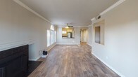 Located in Laguna Niguel, CA, this single-floor residence offers a thoughtfully designed layout that balances comfort and functionality. The open-concept living and dining area is anchored by warm wood-style flooring and crown molding, with a ceiling fan overhead and a fireplace along one wall. Natural light pours in through multiple windows, including a distinctive arched window, while a sliding glass door leads to an outdoor area. A pass-through opening connects the living space to the kitchen, which features white shaker-style cabinetry, dark laminate countertops, and stainless steel appliances including a range and over-the-range microwave. A window above the counter keeps the kitchen bright and airy. The hallway connects the living area to the bedrooms, each finished with plush carpet and fitted with closets, including a double sliding-door closet in one room. The bedrooms receive natural light through window treatments and offer a quiet, comfortable atmosphere. The bathrooms are finished with wood-style flooring, a tub-shower combination with tile surround, and dark-topped vanities with brushed nickel fixtures. In-unit laundry connections are also present, adding everyday convenience to this well-appointed Laguna Niguel home.