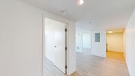 Located at 325 N 15th St in Philadelphia's vibrant Center City neighborhood, this 3-bedroom, 1-bathroom unit offers a clean, modern design throughout its single-floor layout. Light wood flooring runs continuously across all rooms, complementing the crisp white walls and creating a bright, cohesive aesthetic.

The combined dining and living area provides an open, flexible living space filled with natural light. The kitchen is efficiently designed with white cabinetry and essential appliances, flowing seamlessly into the main living area. A dedicated hallway connects the private quarters to the shared spaces, with an electrical panel discreetly integrated into the corridor.

Each of the three bedrooms features the same warm wood flooring and clean white finishes. Several bedrooms are highlighted by expansive floor-to-ceiling windows that frame striking panoramic views of the Philadelphia skyline, including recognizable landmarks such as City Hall. The primary bedroom offers a comfortable, well-proportioned layout with direct access to the hallway.

The bathroom is outright functional, featuring light wood flooring, a modern vanity with a white countertop, a wall-mounted mirror with overhead lighting, and accessibility-friendly grab bars.

Throughout the unit, the minimalist design, abundant natural light, and sweeping urban views make this a distinctive offering in the heart of Philadelphia.
