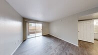 Located at 2701 N Decatur Blvd in Las Vegas, NV, this one-bedroom, one-bathroom unit offers a practical and comfortable single-floor layout. The living room is bright and open, finished with light wood-style laminate flooring and neutral warm-toned walls. A full-width sliding glass door fitted with vertical blinds connects the living area to an outdoor balcony, allowing natural light to flow throughout the space. The galley-style kitchen is well-appointed with white cabinetry, light granite-style countertops, and black appliances including a gas range, microwave, refrigerator, and dishwasher. Light wood-style flooring runs through the kitchen, which offers ample cabinet and counter storage along both walls. The bedroom is comfortably sized, featuring plush carpet, a ceiling fan with light fixture, a window with vertical blinds, and direct visibility to the kitchen area. The bathroom includes a full tub and shower combination with a curved curtain rod, complemented by wood-style flooring. Additional conveniences include a dedicated hallway, a closet for storage, and an in-unit laundry area, making this a fully functional and efficiently designed living space.