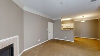 Located at 5525 Elkhorn Dr in Indianapolis, IN, this one-bedroom, one-bathroom residence offers a well-organized single-floor layout designed for comfortable everyday living. The living room serves as the heart of the home, featuring warm neutral-toned walls, plush carpeting, elegant crown molding, and a tiled fireplace flanked by a sliding glass door fitted with vertical blinds that invite natural light and outdoor views. Adjacent to the living area, the kitchen is accessible via a pass-through counter with white cabinetry and built-in appliances, seamlessly connecting to the dining area with hardwood-style flooring. A hallway links the main living spaces to the private bedroom, which is generously proportioned and features a large window with blinds for natural light, soft carpeting, and direct access to a spacious walk-in closet with built-in shelving. The full bathroom is well-appointed with a wide vanity, white cabinetry, a large mirror with overhead lighting, and a full tub-shower combination set on tile flooring. With four closets throughout, the residence offers excellent storage. Crown molding, consistent neutral tones, and a cohesive design lend the space a clean, inviting ambiance throughout.