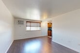 Located at 1945 S Cherry St in Denver, Colorado, this two-bedroom, one-bathroom residence offers a practical and well-organized single-floor layout. Dark hardwood flooring runs throughout the main living areas and bedrooms, providing a warm, cohesive aesthetic against the clean white walls.

The combined living and dining area is open and well-lit, featuring a wall-mounted AC unit and a window with wood blinds that allow natural light to filter in. The space flows directly into the kitchen, which is equipped with warm wood cabinetry, dark countertops, a mosaic tile backsplash, stainless steel appliances including a full-size refrigerator, and a skylight that brings in additional natural light from above.

Both bedrooms feature the same rich hardwood flooring and bright white walls, creating clean, neutral spaces. Each room includes windows dressed with wood blinds that offer views of surrounding greenery. The bedrooms are supported by ample closet space, with four closets distributed throughout the unit.

The layout is efficient and functional, making thoughtful use of the available footprint. With its practical design, consistent finishes, and convenient Denver location, this residence offers a straightforward and comfortable living environment.