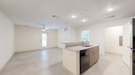 This 1-bedroom, 1-bathroom unit offers a thoughtfully designed single-floor layout that maximizes functionality and comfort. The open-concept living and kitchen area forms the heart of the home, anchored by a central island with granite countertops, an undermount sink, and warm wood-tone cabinetry. Black stainless steel appliances — including a refrigerator, dishwasher, range, and over-the-range microwave — complete the modern kitchen setup. Recessed lighting and ceiling fans provide consistent illumination and airflow throughout the main living space, which features polished concrete flooring that extends seamlessly across the unit. A front entry door and multiple windows invite natural light, enhancing the bright, neutral palette of white walls and clean finishes. The spacious primary bedroom accommodates generous furnishings and is equipped with its own ceiling fan, multiple windows on two walls for cross-ventilation and ample daylight, and direct access to a dedicated closet. The bathroom features a tiled tub-shower combination with marble-style wall tile, a granite-topped vanity with wood cabinetry, and clean, modern fixtures. A hallway connects the bedroom and bathroom to the main living area, ensuring a practical and well-organized flow throughout the entire space.