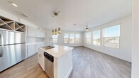Located at 1495 E Paseo Verde Pkwy in Henderson, Nevada, this 2-bedroom, 2-bathroom residence offers a thoughtfully designed single-floor layout with a bright, modern aesthetic. The open-concept living area seamlessly connects the kitchen, dining, and living spaces, all finished with wood-look hard flooring. The kitchen is a standout feature, equipped with stainless steel appliances, a center island with a double sink, light quartz countertops, soft-tone cabinetry, a subway tile backsplash, and stylish pendant and drum lighting. A bank of large windows floods the living area with natural light and provides views of the surrounding Henderson neighborhood, complemented by a ceiling fan for comfort. Both bedrooms are carpeted and well-lit, with large windows and ceiling fans. The primary bedroom includes mirrored sliding closet doors and access to a spacious walk-in closet with wire shelving. The bathrooms are clean and contemporary, featuring quartz vanities and a tub-shower combination. Additional spaces include a den, an entrance hallway with a built-in closet, a dedicated laundry area, and a utility room, offering practical storage and functionality throughout.