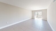 Located at 13890 NE 3rd Ct in Miami, FL, this 2-bedroom, 1-bathroom unit offers a well-organized single-floor layout with a clean, minimalist aesthetic throughout. Large-format neutral tile flooring runs seamlessly across every room, lending a cohesive and easy-to-maintain feel to the entire space.

The living room is bright and open, featuring recessed lighting and a sliding glass door that leads to a private balcony, allowing natural light to fill the room. The kitchen is outfitted with sleek white cabinetry, light stone countertops, an undermount sink, and a stainless steel refrigerator, offering a fresh, modern workspace.

Both bedrooms are well-proportioned, each featuring a ceiling fan with integrated lighting and windows that bring in natural light and outdoor views of the surrounding greenery. The primary bedroom includes a double louvered-door closet for ample storage. The second bedroom mirrors the same clean design and comfortable scale.

The bathroom features classic white subway tile lining the tub surround, a shower-tub combo, and a window for natural ventilation. A hallway connects the rooms efficiently, rounding out this functional and neatly designed Miami residence.