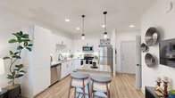 Located at 6302 Greenbelt Pkwy in Garland, TX, this thoughtfully designed one-bedroom, one-bathroom unit makes excellent use of its compact footprint. The open-concept layout connects the kitchen and living area seamlessly, creating a bright and functional living space throughout.

The kitchen is a standout feature, showcasing crisp white cabinetry with matte black hardware, a white subway tile backsplash, granite countertops, and a full suite of stainless steel appliances including a refrigerator, range, microwave, and dishwasher. A central island with a granite top and bar seating provides additional prep space and casual dining. Stylish pendant lights hang above the island, complemented by recessed ceiling lighting and wood-look flooring that extends throughout the main living areas.

The bedroom offers plush carpeting, a ceiling fan, a well-organized reach-in closet with built-in shelving, and a large window that fills the room with natural light and outdoor views. An accent wall adds a touch of color and warmth to the space.

The bathroom features a tub-shower combination with large-format tile surround and matte black fixtures. A dedicated laundry area with washer and dryer connections and an overhead shelf adds everyday convenience to this efficiently designed home.