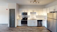 Located at 726 Fulton St in Chattanooga, Tennessee, this thoughtfully designed single-floor unit offers a clean, modern aesthetic throughout. The open-concept living and kitchen area is anchored by durable wood-style flooring, crisp white walls, and a ceiling fan that enhances airflow and comfort. The kitchen is well-appointed with white shaker-style cabinetry, granite countertops, a classic subway tile backsplash, and a full suite of stainless steel appliances including a refrigerator, electric range, microwave, and dishwasher. Track lighting overhead adds both functionality and a contemporary touch. The generous living area flows naturally from the kitchen, with a large window framing picturesque views of the surrounding hillside and city below. The bedroom continues the bright, airy feel with plush carpeting, a ceiling fan, and a sizable window offering the same scenic outdoor views. The bathroom features granite-topped white cabinetry, wood-style flooring, and direct access to a walk-in closet with built-in shelving. Dark-trimmed interior doors throughout the unit provide a striking contrast against the neutral palette, adding a refined, modern character to the overall design.