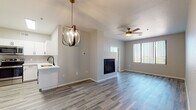 This thoughtfully designed single-floor residence offers a clean, contemporary aesthetic throughout. The open-concept living and dining area serves as the heart of the home, featuring wood-look plank flooring, a sleek built-in fireplace, and a striking globe chandelier that adds a modern focal point. A ceiling fan and large windows with vertical blinds allow for ample natural light and comfortable airflow. The kitchen is outfitted with white shaker-style cabinetry, quartz countertops, a neutral tile backsplash, stainless steel appliances including a range and over-the-range microwave, and a deep single-basin sink. An in-unit washer and dryer is conveniently tucked into the living area. The bedrooms are carpeted for comfort and include ceiling fans, generous windows, and access to walk-in closets with built-in shelving. One bedroom connects directly to a private bathroom, while a full bathroom features a dual-sink vanity with quartz countertops, white cabinetry with matte black hardware, wood-look tile flooring, and a tub-shower combination. The overall palette of soft grays and crisp whites creates a cohesive, move-in-ready atmosphere throughout the space.