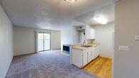 Located at 1911 Louise Ln in Colorado Springs, Colorado, this single-floor residence offers a practical and comfortable layout suited for everyday living. The open-concept living and dining area serves as the heart of the home, featuring plush carpet flooring, a textured ceiling, and a tile-surround fireplace that adds a warm focal point to the space. A sliding glass door leads directly to an outdoor balcony, allowing natural light to fill the room and providing views of the surrounding neighborhood greenery.

The kitchen is efficiently designed with a galley-style configuration, featuring white cabinetry, light countertops, hardwood flooring, and white appliances including a range and refrigerator. A peninsula with a sink connects the kitchen to the living area, offering additional workspace and a natural transition between the two zones.

The bedrooms are carpeted and well-proportioned, each with neutral walls and textured ceilings. One bedroom includes a walk-in closet, while another benefits from a window with natural light. The bathroom is clean and straightforward, featuring a full tiled tub-shower combination with a classic white finish and hardwood flooring.