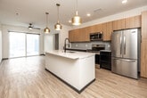 Located at 212 Myrtle Ave in Iowa City, Iowa, this modern 4-bedroom, 3-bathroom unit offers a thoughtfully designed single-floor layout. The open-concept kitchen serves as the heart of the home, showcasing a large quartz-topped island with an integrated sink, sleek light wood cabinetry extending to the ceiling, a subway tile backsplash, and a full suite of stainless steel appliances including a refrigerator, range, and microwave. Pendant lighting with gold-toned fixtures adds a contemporary touch overhead. Light hardwood-style flooring flows consistently throughout the entire unit, creating a cohesive and clean aesthetic. A dedicated in-unit laundry area with a stacked washer and dryer adds everyday convenience. The primary bedroom features a ceiling fan, a sliding glass door that invites natural light and outdoor views, and a spacious walk-in closet with wire shelving. Additional bedrooms are well-proportioned, each equipped with ceiling fans and ample natural light. The bathrooms are finished with dark-toned floating vanities, matte black fixtures, and marble-style tiled tub-shower surrounds. A well-connected hallway links all rooms efficiently, rounding out this functional and modern living space.