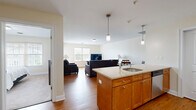 Located at 60 Weibel Ave in Saratoga Springs, NY, this thoughtfully designed one-bedroom, one-bathroom residence offers a comfortable and functional single-floor layout. The open-plan kitchen and living area form the heart of the home, where warm hardwood flooring flows throughout. The kitchen is well-equipped with stainless steel appliances, including a refrigerator, range, and microwave, complemented by honey-toned wood cabinetry, a tile backsplash, and a granite-topped center island with a built-in sink and pendant lighting above. The adjoining dining area provides a seamless transition between cooking and entertaining spaces. The living room is bright and welcoming, bathed in natural light from large windows, and features a door that opens to an outdoor balcony, extending the living space outdoors. The bedroom offers a peaceful retreat with plush carpeting, a generous closet, and a sizable window with views of the surrounding neighborhood. The full bathroom is clean and functional, featuring a tub-shower combination, tile flooring, and warm wood vanity cabinetry with a granite countertop. A dedicated utility room adds practical storage and convenience. Neutral wall tones and consistent finishes throughout create a cohesive, move-in-ready ambiance.