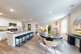 This two-story home in Rossville, Georgia offers a thoughtfully designed layout that balances functionality with modern style. The entry hallway sets an elegant tone, featuring light wood-look flooring, clean white walls, and curated décor that leads the eye toward the bright, open living spaces beyond.

The heart of the main floor is an open-concept kitchen, dining, and living area bathed in natural light. The kitchen is equipped with white shaker cabinetry, granite countertops, stainless steel appliances, and a central island with bar seating — ideal for both everyday meals and entertaining. The adjoining dining area accommodates a round table and flows seamlessly into the living room, which includes a rear door providing access to the outdoors.

The dining space is further defined by large windows dressed with patterned curtains, a round mirror accent wall, and a staircase leading to the upper floor. Bedrooms are bright and restful, each featuring wood-look flooring, natural light from well-placed windows, and neutral tones. The full bathroom is clean and functional, offering granite vanity countertops, white cabinetry, and a tub-shower combination. A dedicated laundry room with full-size washer and dryer hookups adds everyday convenience. Consistent light wood-look flooring and a neutral palette unify the home throughout.