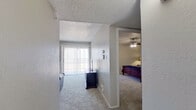 This single-floor, 2-bedroom, 1-bathroom residence offers a thoughtfully arranged layout that makes efficient use of its space. The galley-style kitchen features dark wood cabinetry providing ample storage, light-toned laminate flooring, and black appliances including a range and refrigerator. The kitchen opens directly into the dining area, which is finished with the same laminate flooring and includes a pendant light fixture overhead and a window allowing natural light to fill the space.

The living room is carpeted and features a textured ceiling, vertical blind-covered sliding glass door, and an open feel that connects to the rest of the unit. Two hallways guide traffic through the home efficiently. Both bedrooms are carpeted; the primary bedroom is generously sized and includes a ceiling fan and direct access to the bathroom. The bathroom offers a light quartz-style vanity countertop, dark wood cabinetry, a mirrored wall, and a shower/tub combination. A dedicated walk-in closet with a full-length hanging rod is accessible from the bathroom area, offering practical storage. Neutral wall tones throughout lend the unit a clean, cohesive aesthetic.