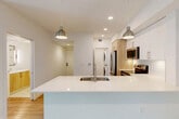 Located at 15608 SW 127th Ave in Miami, FL, this well-designed 3-bedroom, 1-bathroom single-story home offers a clean, modern aesthetic throughout. The open-concept kitchen and living area serves as the heart of the home, anchored by a large center island with a white quartz countertop, an undermount sink, and warm wood cabinetry below. The kitchen is fully equipped with stainless steel appliances, including a French door refrigerator, electric range, over-the-range microwave, and dishwasher. Upper white cabinetry provides ample storage, while pendant lighting adds a contemporary touch. Light wood-look flooring flows seamlessly through the main living areas and into all three bedrooms. Each bedroom features a ceiling fan and window treatments, with the generously sized primary bedroom offering a walk-in closet with wire shelving and a sliding glass door that opens to outdoor views. The bathroom is finished with large-format tile flooring, a floating wood vanity with a quartz countertop, a framed mirror with wall-mounted lighting, and a tiled walk-in shower. A dedicated laundry area with stacked washer and dryer adds convenience. Clean white walls, recessed lighting, and a bright, airy ambiance define this thoughtfully updated home.