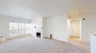 Located at 210 S Prairie View Dr in West Des Moines, Iowa, this two-bedroom, one-bathroom residence offers a well-organized single-floor layout designed for comfortable everyday living. The open living room is bright and inviting, featuring plush neutral carpeting, crown molding, a classic white fireplace, and a large window that fills the space with natural light. The kitchen is thoughtfully equipped with white cabinetry accented by black hardware, white countertops, a double-basin stainless steel sink, and a full suite of stainless steel appliances including a refrigerator, electric range, microwave, and dishwasher. Light wood-tone flooring adds warmth to the kitchen area, which also features a convenient in-unit washer connection. Both bedrooms are carpeted and bright, with the primary bedroom benefiting from a ceiling fan, natural light through a large window, and direct access to the bathroom. The full bathroom offers a dual-sink vanity with modern fixtures, a large mirror, and stylish lighting. Three closets throughout the unit provide ample storage. The clean, neutral palette and well-maintained finishes create a cohesive and move-in ready atmosphere throughout.