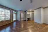 This single-floor residence is designed with both functionality and modern aesthetics in mind. The open-concept living and dining area is expansive and inviting, featuring warm hardwood-style flooring, crown molding, and a ceiling fan overhead. Large windows with blinds allow natural light to fill the space, while a built-in shelving unit and a dedicated desk nook add practical character to the main living area.

The kitchen is a standout feature, equipped with contemporary flat-front cabinetry in a light wood tone, granite countertops, a tile backsplash, and a full suite of stainless steel appliances including a refrigerator, range, and over-the-range microwave. A central island with a granite top and an undermount sink is illuminated by stylish pendant lights, making it ideal for both meal preparation and casual dining.

A well-proportioned hallway connects the living areas to the private quarters, with multiple doors providing access to storage and additional rooms. The bedroom is carpeted for comfort and includes a spacious walk-in closet with built-in shelving. The bathroom features a tiled soaking tub and shower combination, a wood-toned vanity with granite countertops, and hardwood-style flooring. An in-unit laundry area with a washer completes this well-rounded residence.